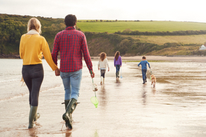 A family and a pet dog walking along a beach