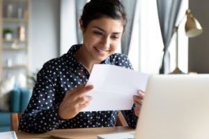 A woman smiling as she looks at paperwork.