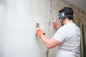 A tradesperson repairing a crack in a wall.